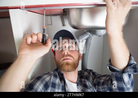 handsome plumber repairing sink Stock Photo