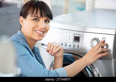 close-up of woman pressing button of washing machine Stock Photo