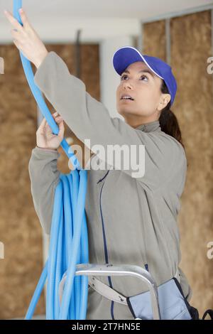 female electrician installing ventilation pipese in ceiling Stock Photo