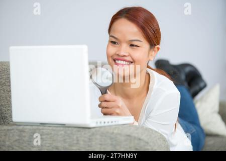 businesswoman looking at laptop through magnifying glass Stock Photo