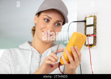 female electrician testing a wall socket Stock Photo