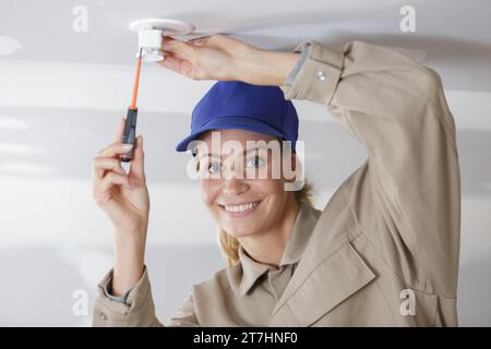 woman installing a light bulb in the ceiling Stock Photo