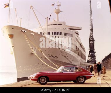 1966 newly launched Jaguar E-type Series 1 2+2 next to luxury ocean liner SS Canberra at Southampton Docks with family of four Stock Photo