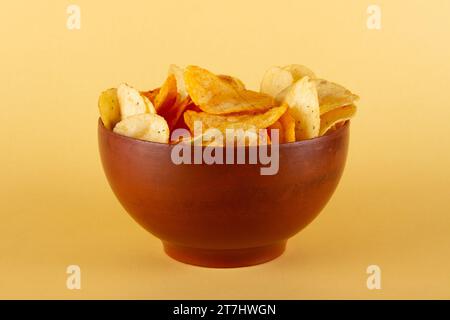 Potato chips in clay bowl isolated on beige background. side view Stock Photo