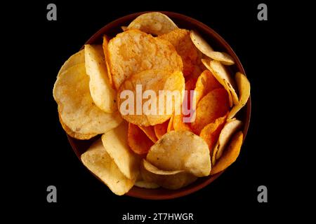 Potato chips in clay bowl isolated on black background. Top view Stock Photo