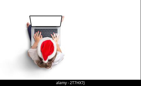 Top view of girl in Christmas hat works on laptop with isolated screen for mockup. Copy space Stock Photo