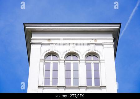 White facade of an old building against a blue sky. Stock Photo