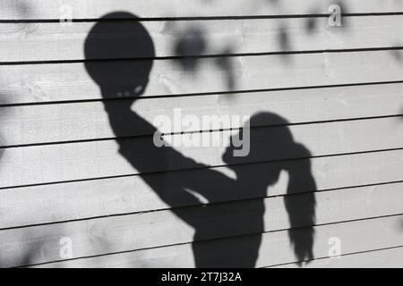 Shadow of a teenage girl holding volleyball in front of grey background Stock Photo