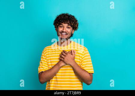 Photo portrait of attractive young man touch chest heart grateful dressed stylish striped yellow clothes isolated on cyan color background Stock Photo