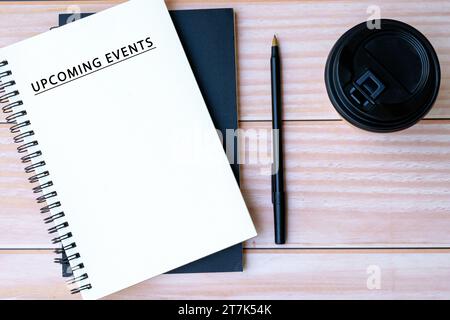 Upcoming events text on notepad with pen and disposable coffee cup a desk Stock Photo