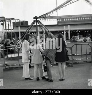 1970s, four young women at a fairground, standing together, watching the activity, England, UK, Stock Photo