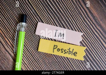 Concept of Im Possible write on sticky notes isolated on Wooden Table. Stock Photo