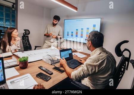 Multiracial Team of Architects and Engineers Discussing Blueprint in Business Meeting Stock Photo