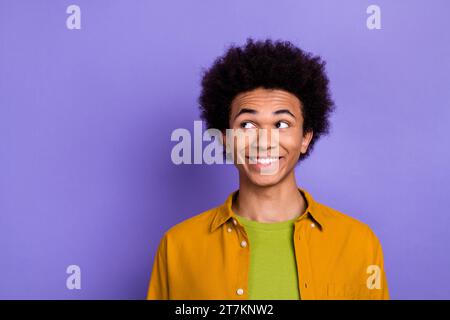 Photo of positive good mood glad man wear stylish yellow clothes look up banner empty space isolated on violet color background Stock Photo