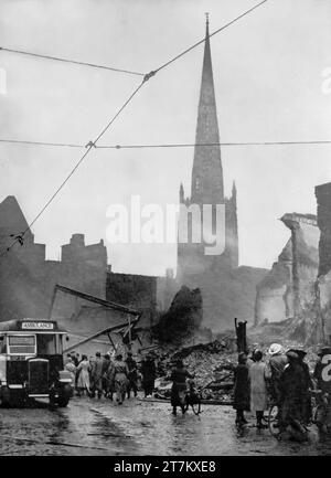 The morning of the 14th November 1940, and people in Coventry, England survey the damage caused by the previous nights Luftwaffe air raids during the Second World War. Happily the city's cathedral spire is still standing Stock Photo