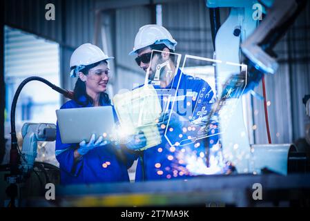 Two engineers mechanic using computer controller Robotic arm for welding steel in steel factory workshop. Industry robot programming software for auto Stock Photo