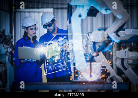 Two engineers mechanic using computer controller Robotic arm for welding steel in steel factory workshop. Industry robot programming software for auto Stock Photo