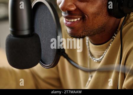 Smile of young African American male host speaking in microphone while making podcast or interview with guest for online audience Stock Photo