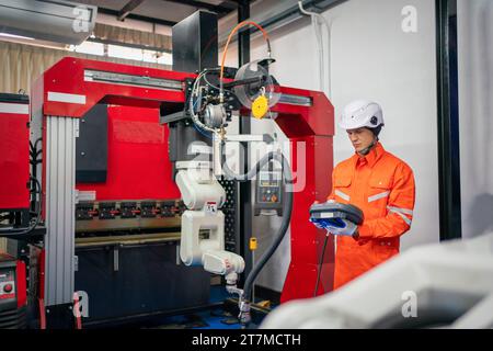 Engineers mechanic using computer controller Robotic arm for welding steel in steel factory workshop. Industry robot programming software for automate Stock Photo