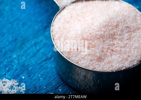 Himalayan salt in measuring spoon on wooden background. Pink salt. Stock Photo