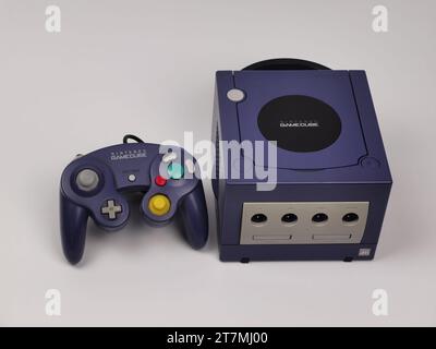 A Purple Nintendo GameCube console with a purple joypad on a white background. Stock Photo