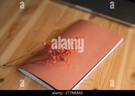 Pink closed notepad with dried flowers on a wooden table on a wooden table Stock Photo
