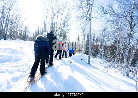 Snowshoeing through a snowy forest on large traditional wooden snowshoes, Yellowknife, Northwest Territories, Canada Stock Photo