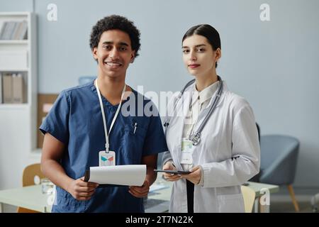 Waist up portrait of two young medical interns looking at camera standing in clinic office, copy space Stock Photo