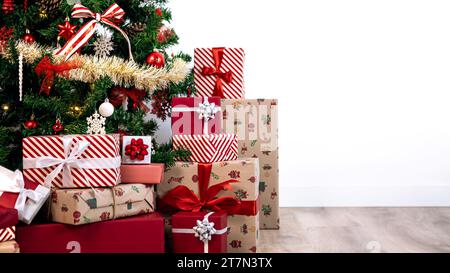 Neatly wrapped gift boxes beneath the contemporary Christmas tree in a home, against isolated white background with empty copy space for text, complem Stock Photo