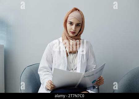 Minimal portrait of young Muslim woman as female doctor wearing headscarf in clinic and looking at camera, copy space Stock Photo