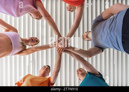 diverse group of people in a circle, hands together in a gym Stock Photo