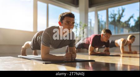 Side view of a muscular people doing planking exercises in gym on a yoga mat Stock Photo