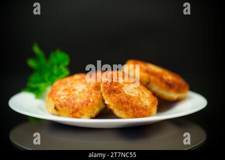 Cooked fried fish cutlets in a plate with herbs, isolated on a black background. Stock Photo
