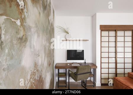 Modern Japandi appartment interior design in earth tones, natural textures with wooden solid oak desk and clay decorative wall. Japandi concept Stock Photo