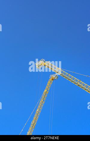 Jibs of two tower cranes isolated against a deep blue sky. No people. Stock Photo