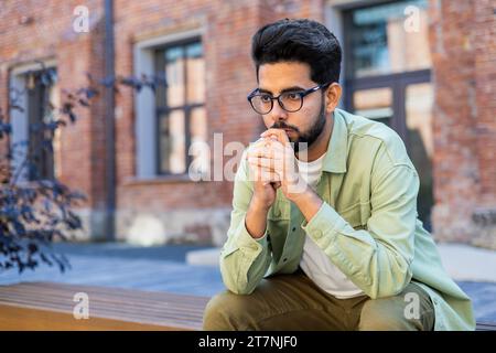 Sad depressed man sitting on bench outside office building, businessman disappointed with achievement results, unhappy man. Stock Photo