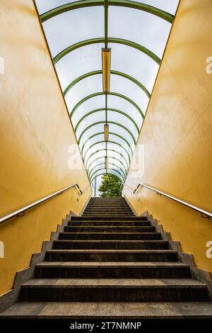 Small tunnel with yellow walls and green arcs and with downstairs to underground passage under streets Stock Photo