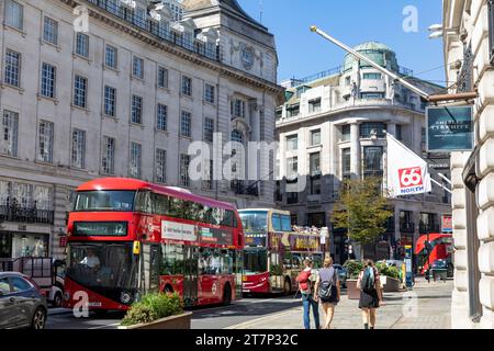 Regent street London, double decker red bus and sightseeing tour bus, shoppers walk past 66 north Icelandic store,London,England,UK,2023 Stock Photo