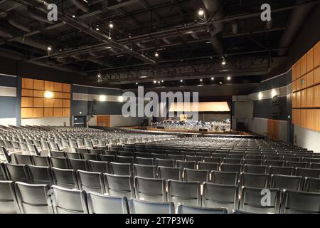 A modern theater in a high school with accoustical panels, stage lighting, and folding seats. Stock Photo