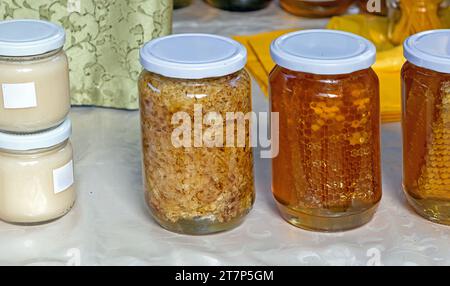 Royal jelly honey comb and other bee products in glass jars sold on market stall Stock Photo