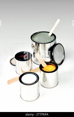 Cans of white, yellow, burgundy, and grey paint with stirring sticks on a studio white background. Stock Photo