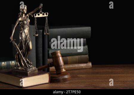 Symbol of fair treatment under law. Statue of Lady Justice near books and gavel on wooden table, space for text. Stock Photo