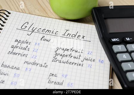 Notebook with products of low, moderate and high glycemic index, calculator and apple on table, closeup Stock Photo