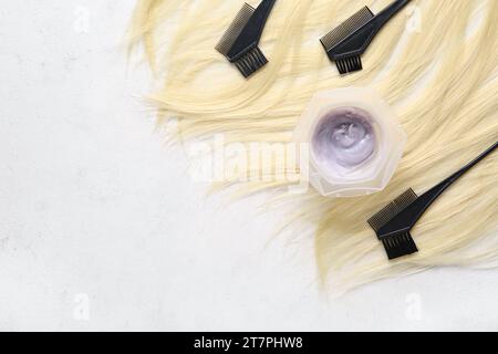 Bowl with hair dye, brushes and blond strand on white background Stock Photo