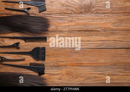 Hairdresser's tools and strands of brunette hair on wooden background Stock Photo