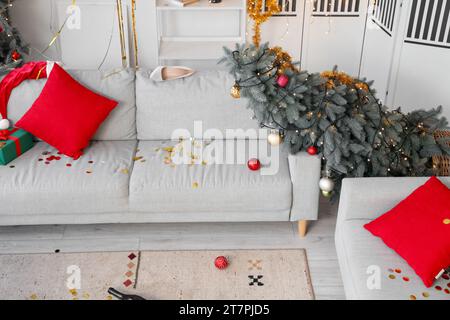 Interior of messy living room after New Year party with fallen Christmas tree Stock Photo