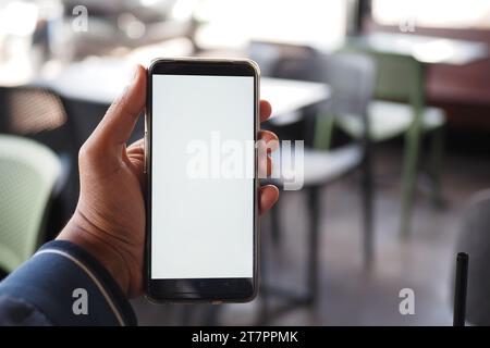 young man hand using smart phone with white screen at cafe background  Stock Photo