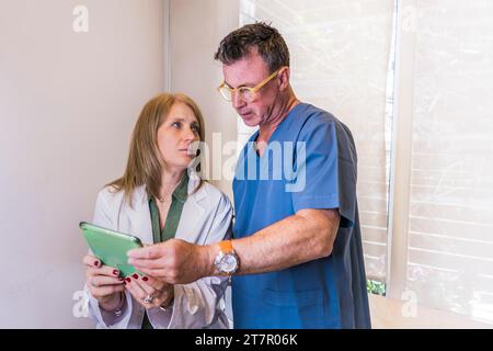 Mid-adult doctors looking at tablet while discussing a patient diagnosis Stock Photo