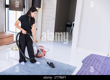Woman maid home cleaning doing chore, House wife vacuum clean up dust floor carpet in bedroom. Stock Photo