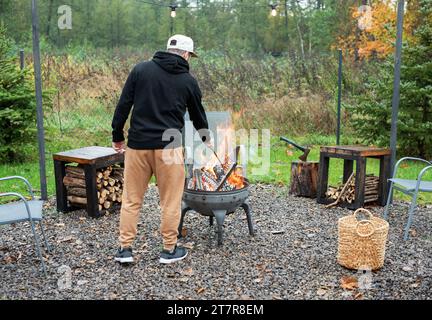 A man lights a barbecue in nature near the house Stock Photo